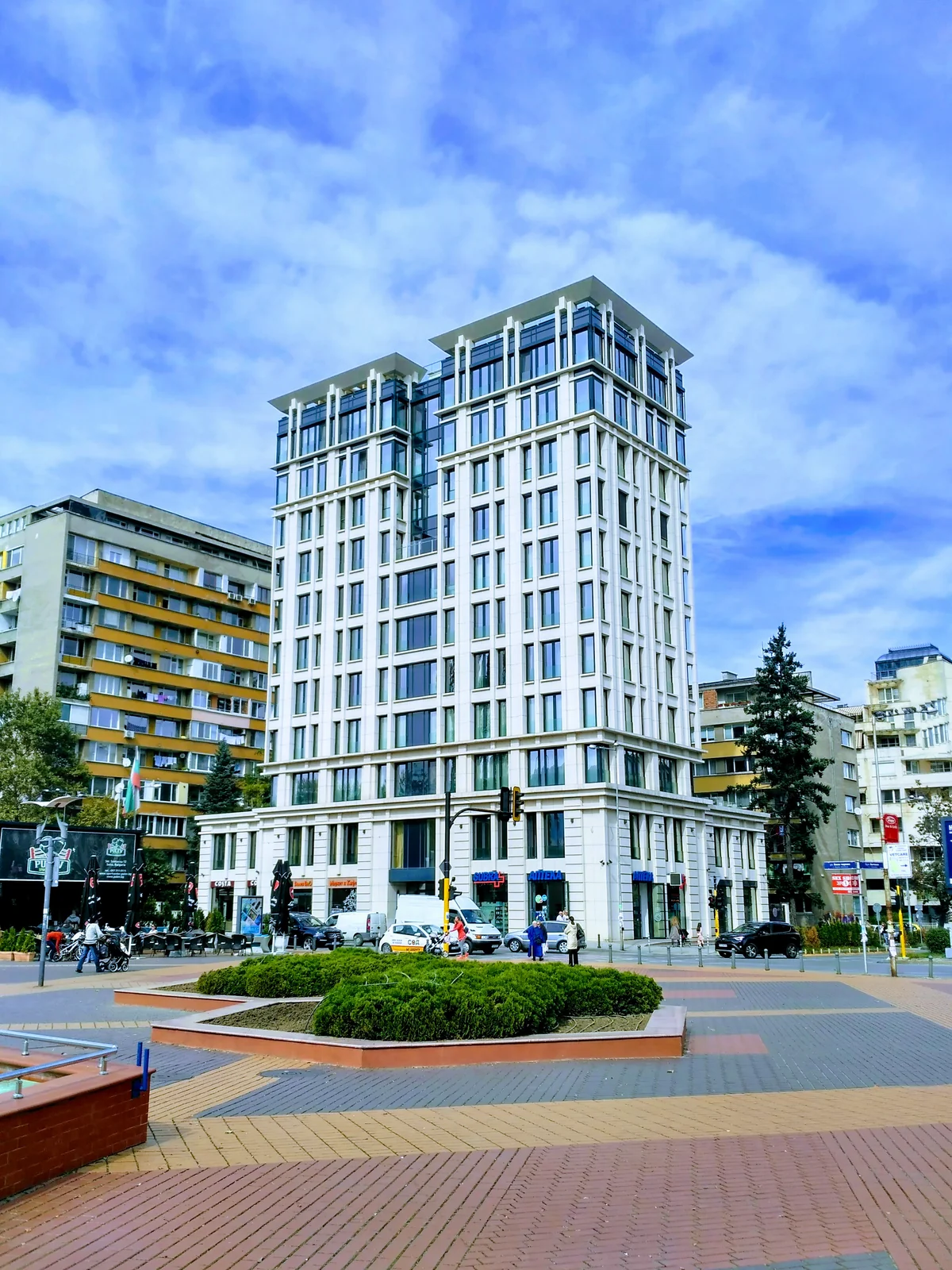 Contemporary multi-story architecture with ground floor pharmacy and pedestrian plaza in Sofia